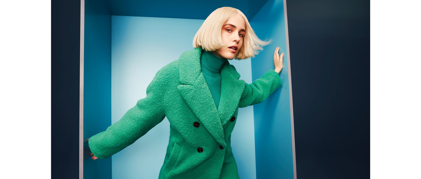 A stylish woman showcasing a trendy blonde bob haircut, embodying the season's fresh hairstyling trends.